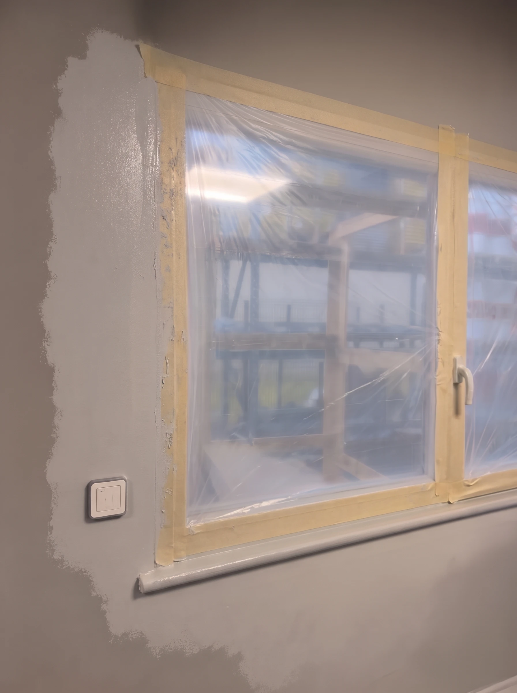 Fenêtre protégée par un polyane de protection fixé à l'adhésif de masquage pendant la peinture du mur